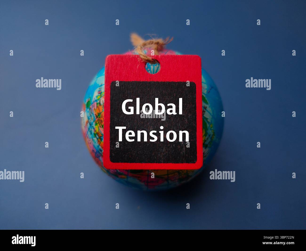 Erdkugel von oben und Holzbrett mit dem Wort Globale Spannung auf blauem Hintergrund. Stockfoto