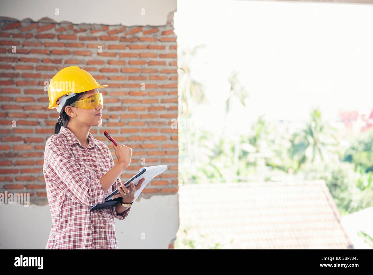 Bauingenieurin trägt einen weißen Schutzhelm bei Baustellenarbeitern. Ingenieurin mit Schutzhelm sa Stockfoto