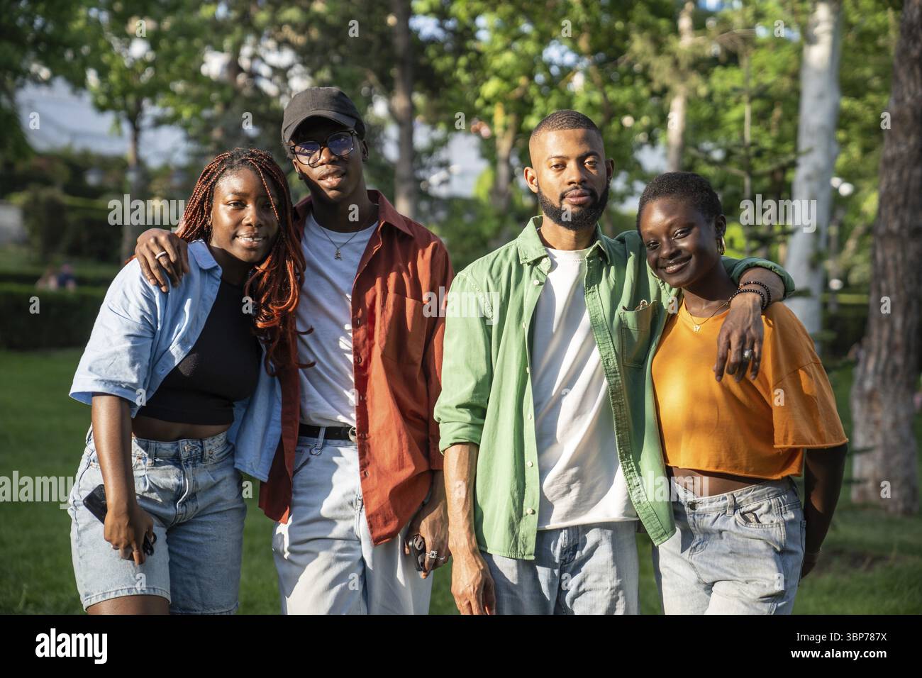 Glückliche, zufriedene Gruppe afroamerikanischer Freunde hört auf zu laufen und blickt mit einem Lächeln in die Kamera. Interessierte, zufriedene Studenten, schwarze Mädchen und Jungs, während St. Stockfoto