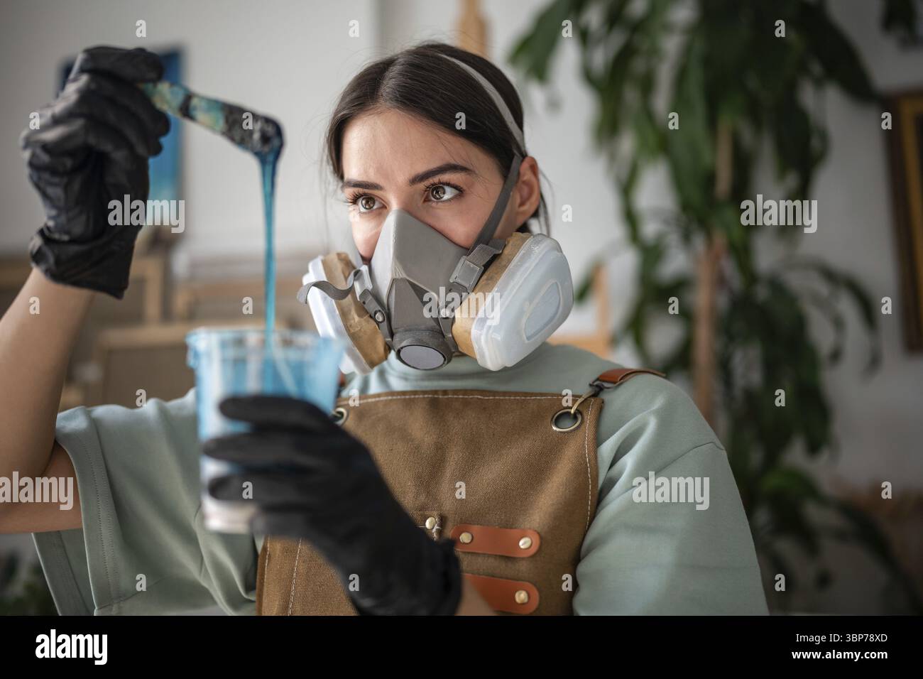 Professionelle Künstlerin rührt Epoxidharz, bewertet Dicke und Konsistenz, um in der Technik der flüssigen Kunst zu arbeiten. Frau, die Flüssigkeit mischt Stockfoto