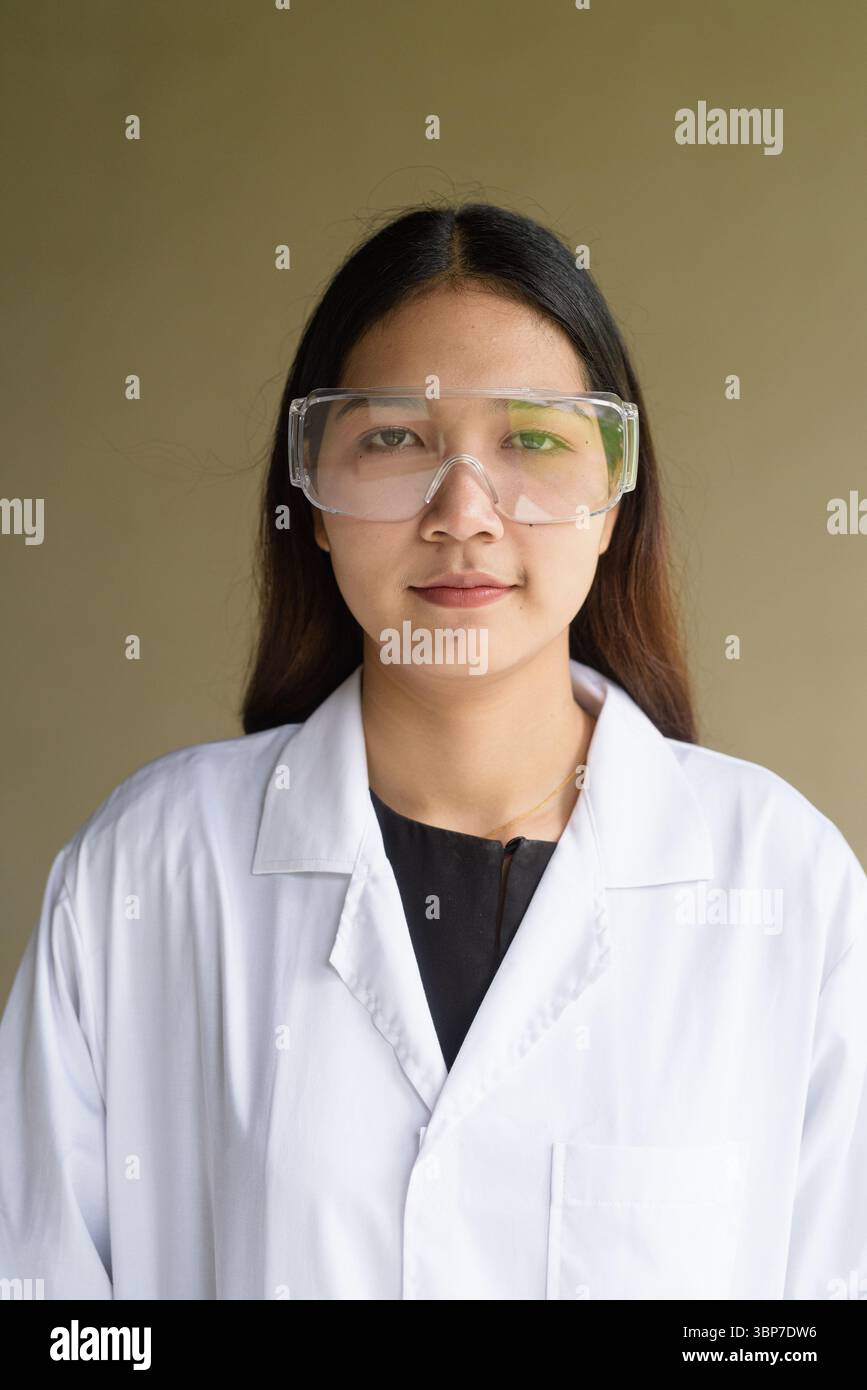 Junge asiatische Wissenschaftlerin mit Labormantel und Schutzbrille Stockfoto