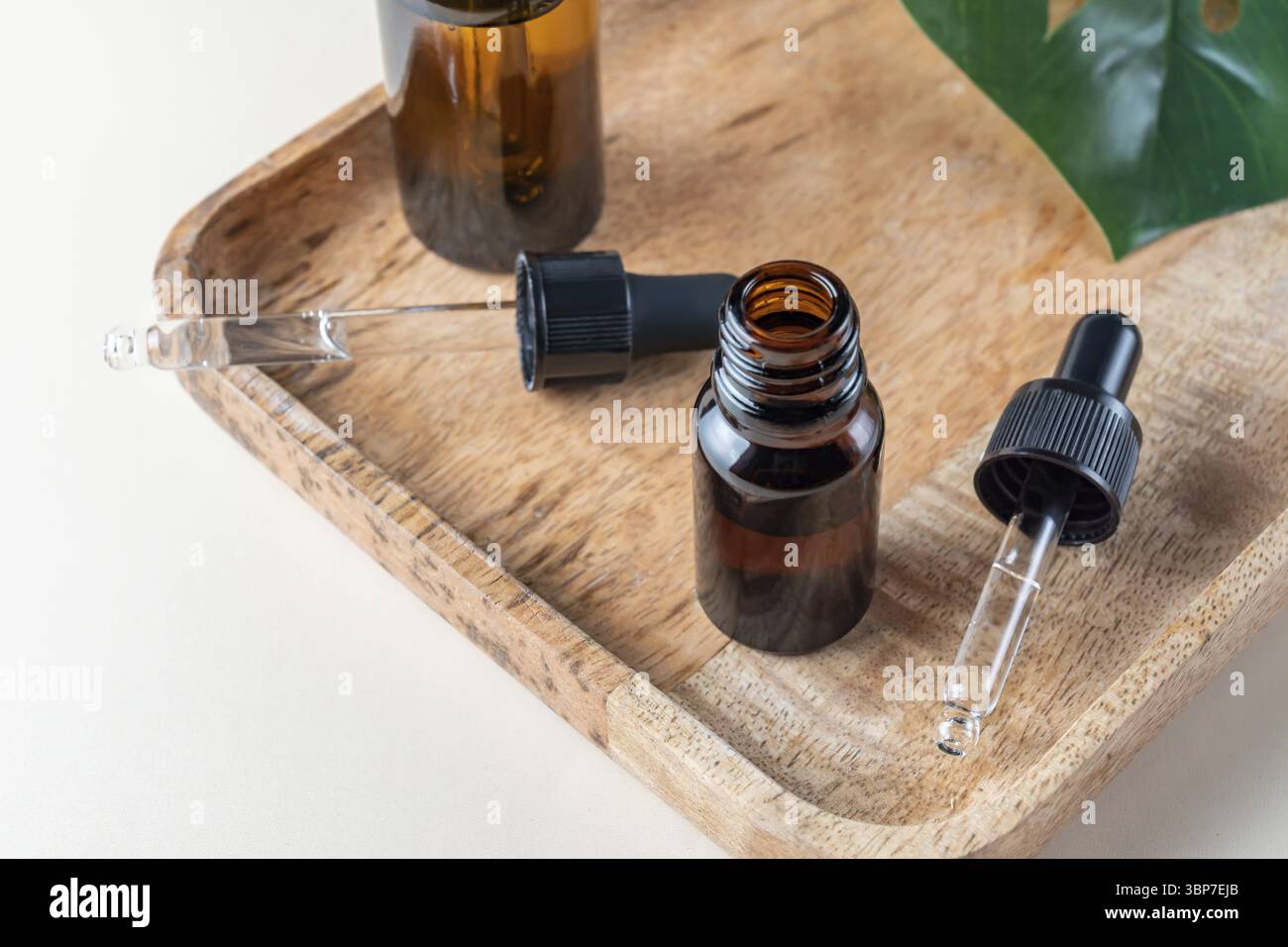 Bio-Spa mit Naturkosmetik in minimalistischem Stil. Kosmetisches Serum, Gesichtshaut-Pflegeöl in dunklen Glasflaschen auf Holzschale Stockfoto