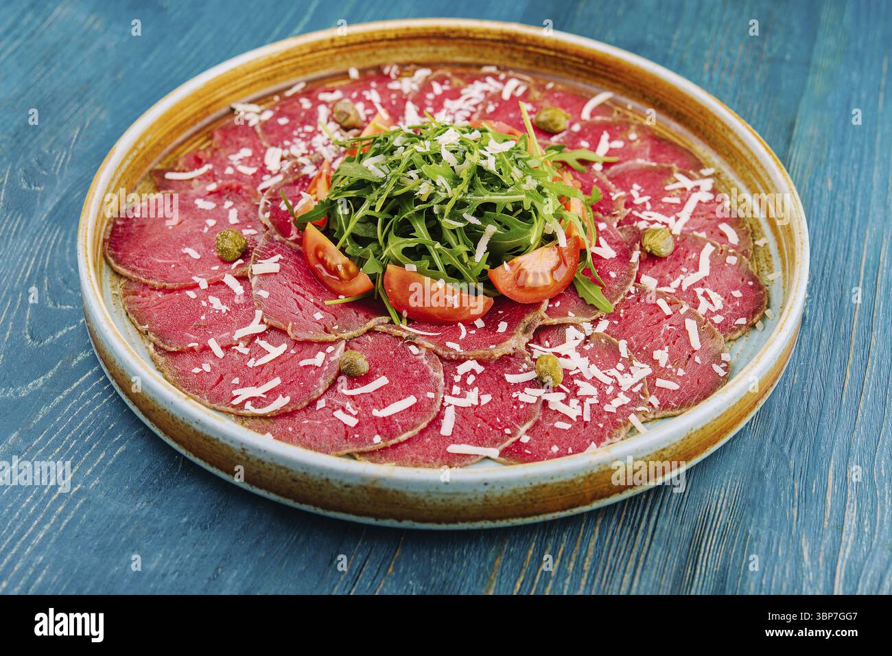 Essen, Carpaccio vom Rind mit Kapern, Parmesan, Rucola und Tomaten Stockfoto