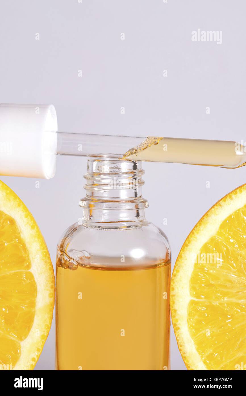 Vitamin-C-Serum in kosmetischen Flaschen mit orangen Zitrusscheiben mit auf weissem Hintergrund. Aetherisches Oel von Zitrusfruechten, Kosmetik Aromathe Stockfoto