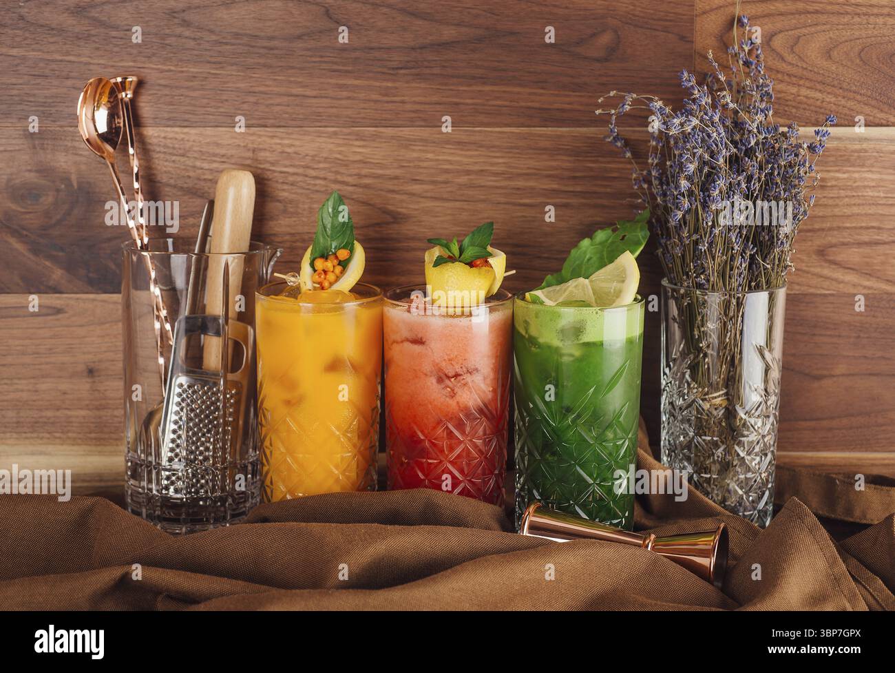 Essen, drei bunte Cocktails stehen auf einem Tisch mit Cocktailshaker und Lavendel Stockfoto