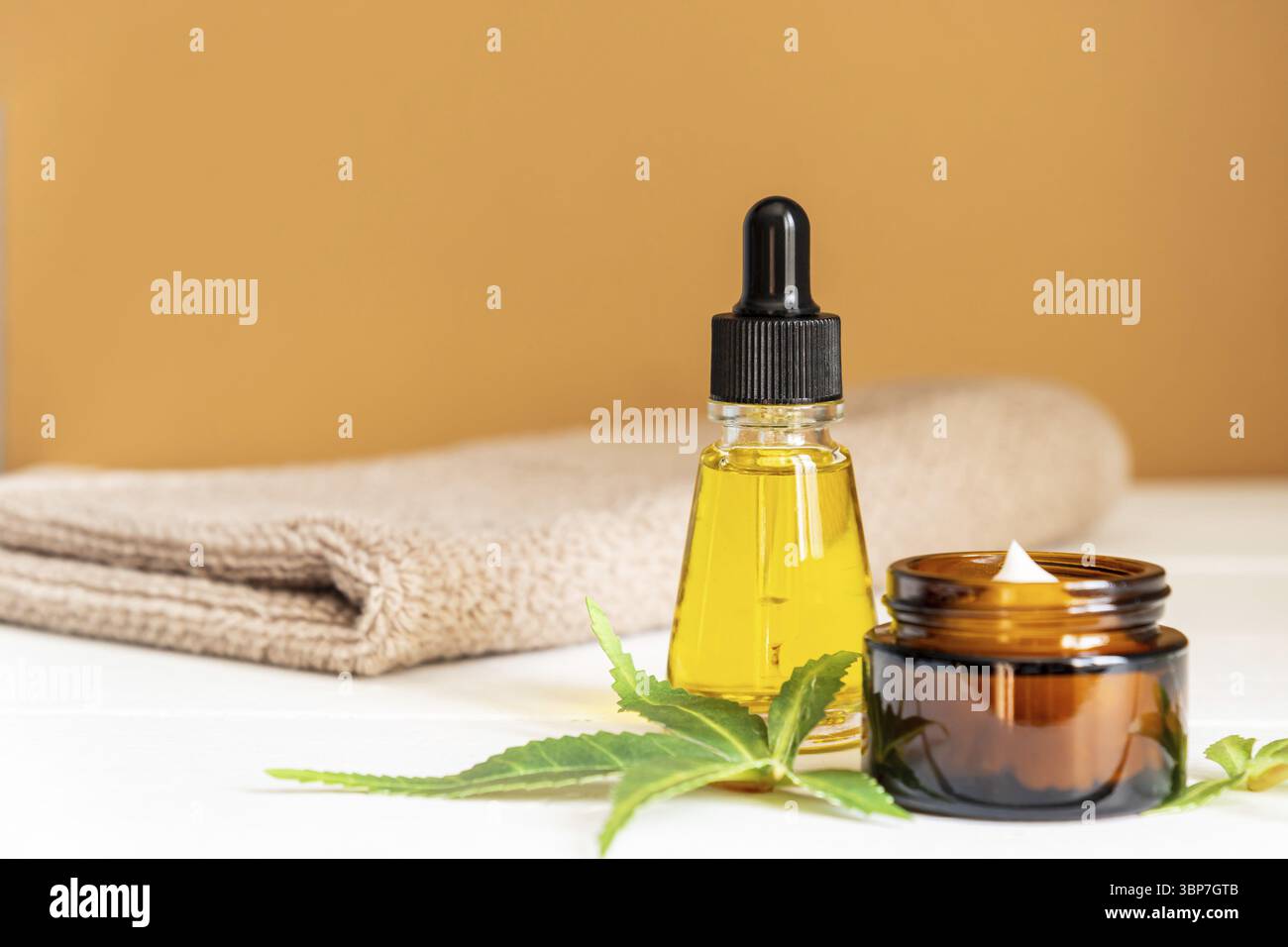 Cannabis Gesichtscreme oder Serum- oder Öltropfenkonzept. Naturkosmetik. CBD-Öl, THC-Tinktur und Hanfblätter auf hölzernem Hintergrund Stockfoto