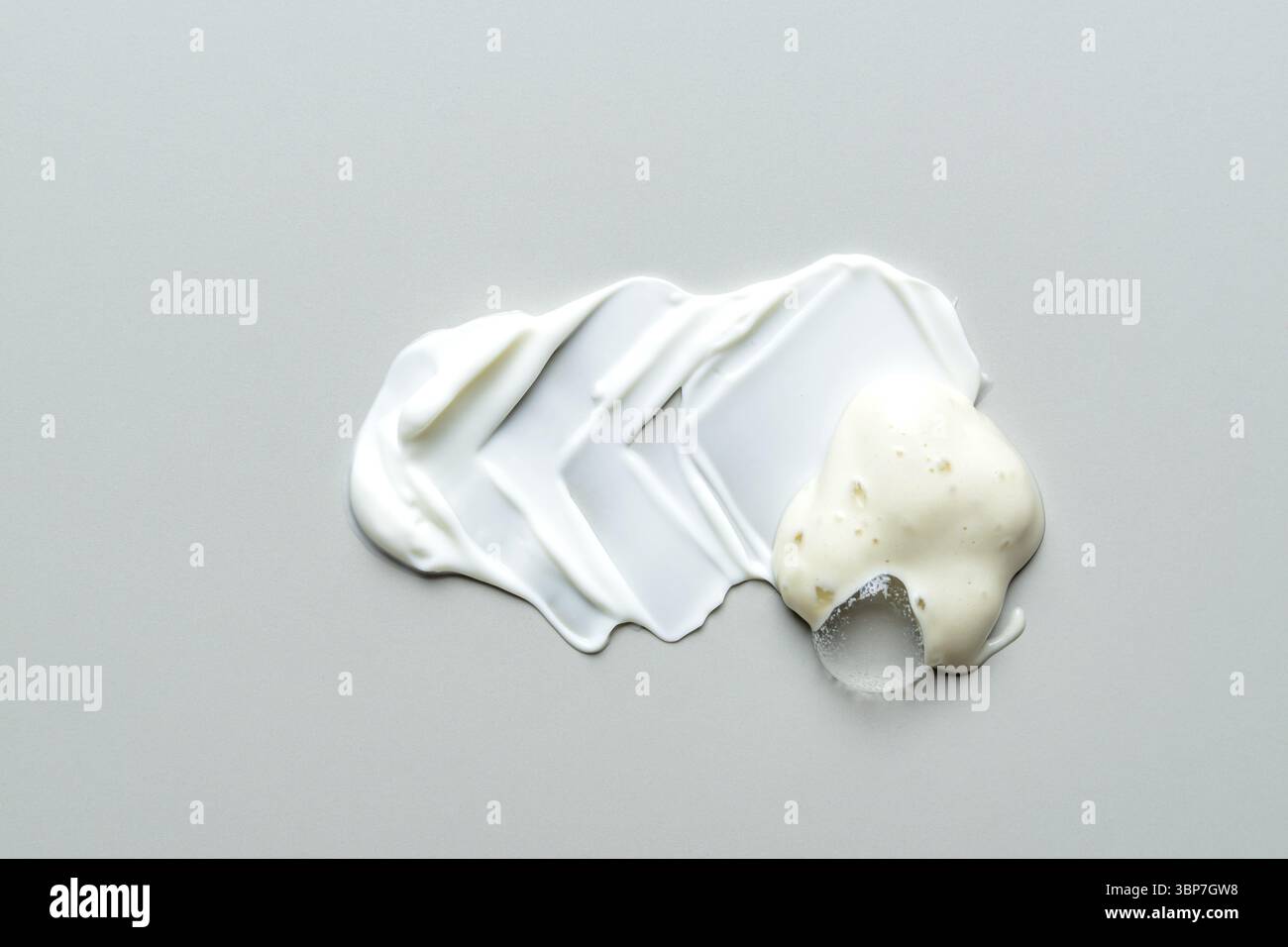 Weißes Gesichtswaschgel und Gesichtsmaske verschmieren auf grauem Hintergrund. Textur des flüssigen Gesichtsreinigers. Hautpflegeprodukt Probe Stockfoto