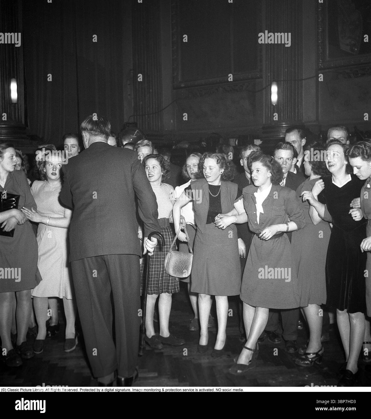 Beim Tanz 1948. Junge Frauen im Tanzpalast Nalen in Stockholm verließen den Abend, um einen Abend voller Tanz und Spaß zu verbringen. Gekleidet in der typischen Mode der 1940er Jahre Die Temperatur steigt, sodass die Eigentümerin des Hotels, Topsy Lindblom, vor ihnen gesehen wird, was die Dinge beruhigt. Kristoffersson Ref. AG44-2 Stockfoto