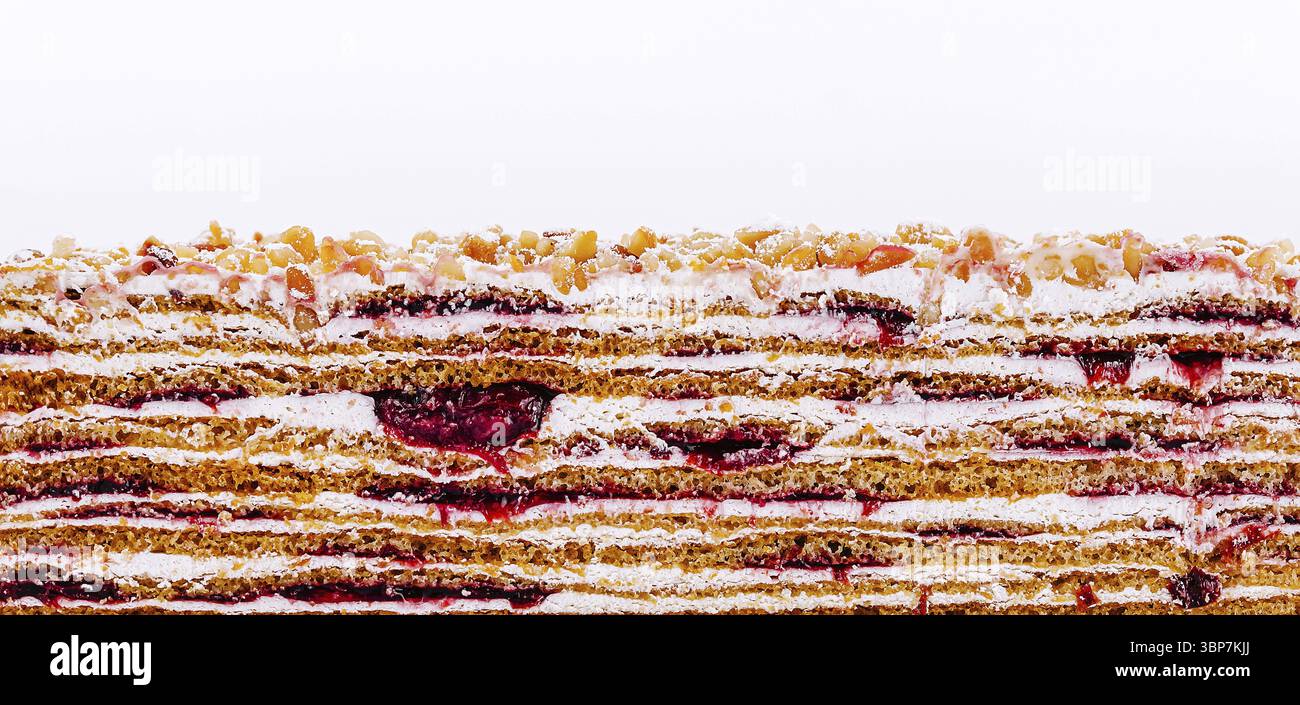 Food, Ein vielschichtiges Dessert mit wechselnden Teigstreifen, Fruchtfüllung und einem Hauch Nüsse darauf. Die lebendigen Farben und Strukturen c Stockfoto
