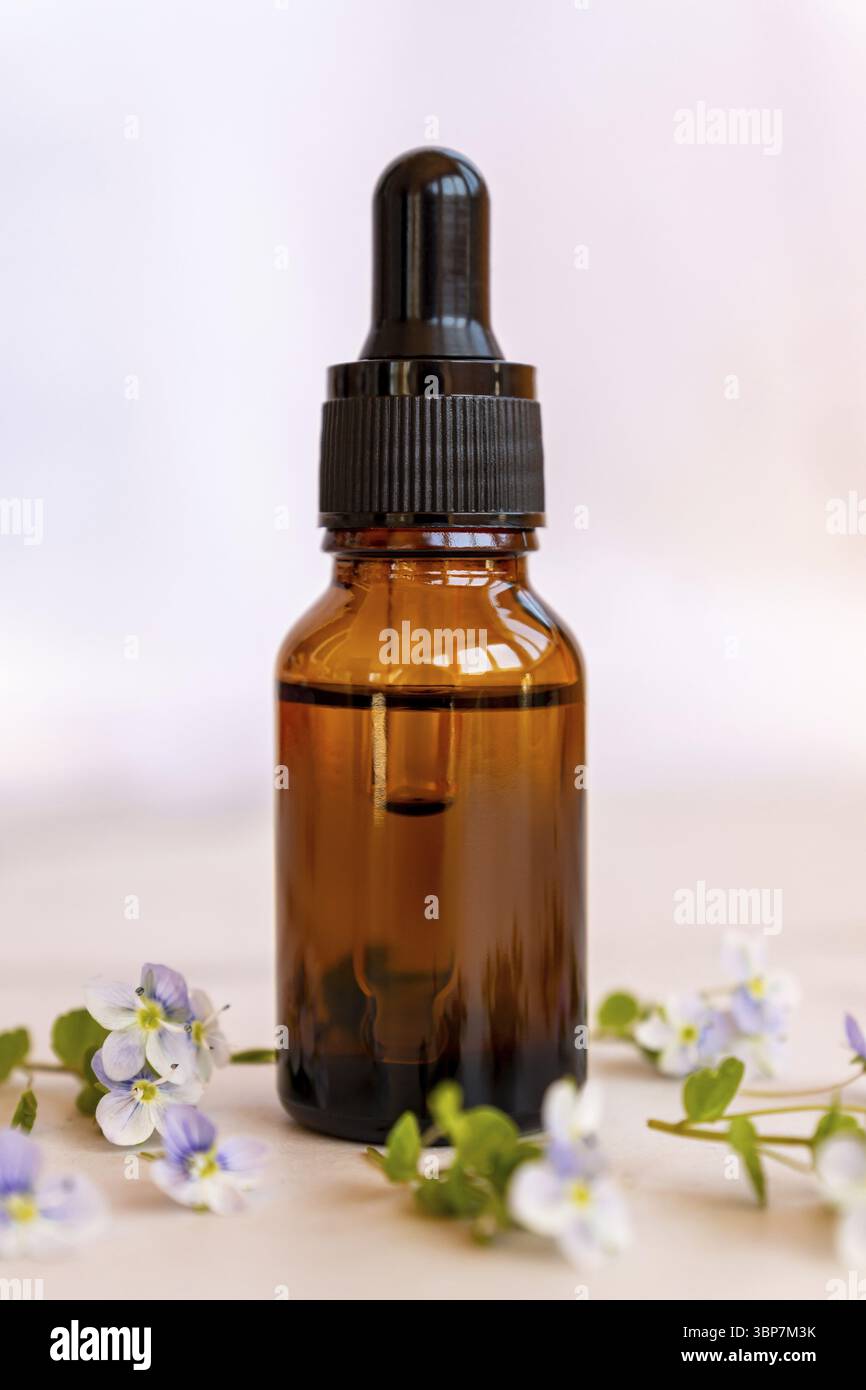 Serumflasche mit Tropf mit wilden Blumen auf Marmorboden. Aromatherapieöl. Natürliches Beauty-Produkt für Haut- oder Körperpflege. Dermatologie und Cosm Stockfoto