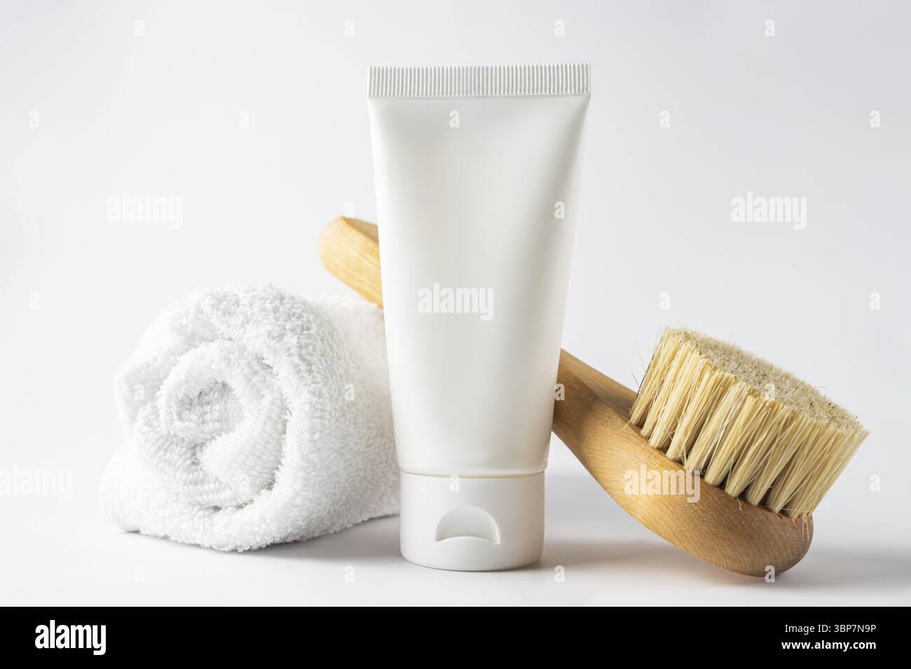 WELLNESS-Kosmetik, Körperpflege für Frauen und Hautpflegeprodukte auf weißem Hintergrund. Naturborsten trockene Massage-Bürste und Körper- oder Gesichtscreme in weißem Kunststoffrohr Stockfoto