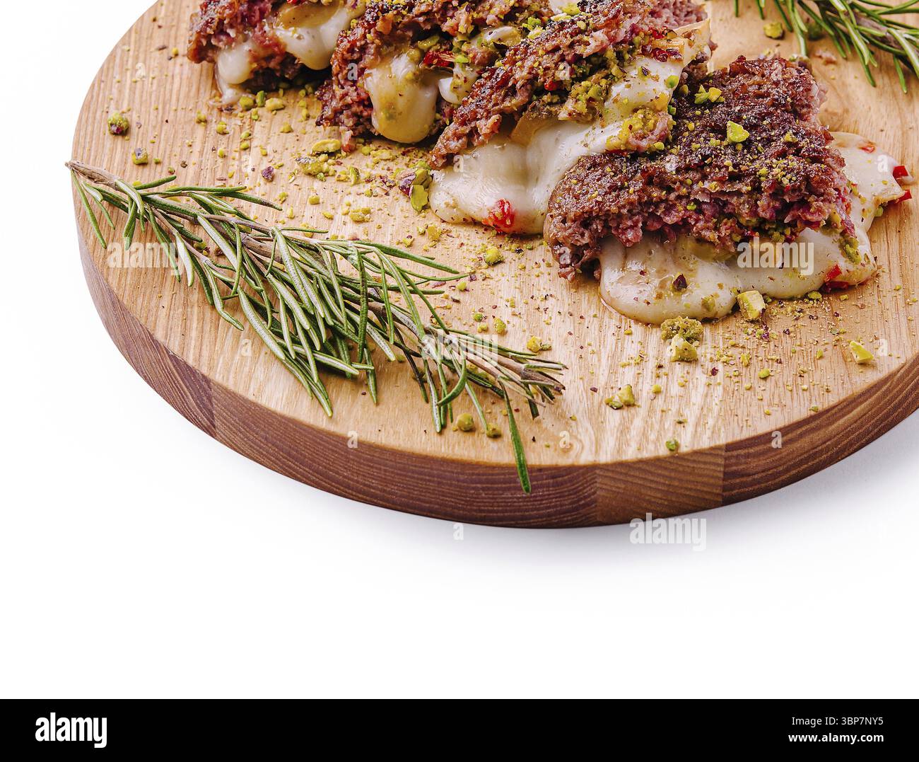 Das Essen, Ein wunderschön präsentiertes herzhaftes Fleischgericht, besteht aus Schichten Käse und Hackfleisch, garniert mit zerstoßenen Nüssen, umgeben von frischen Rosmarinzweigen Stockfoto