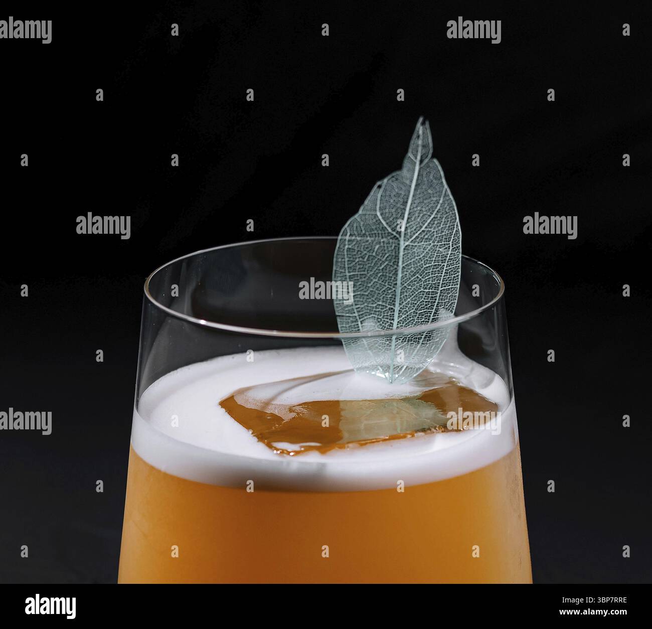 Essen, moderner Cocktail mit einer schaumigen Decke und einer zarten Blattgarnitur, präsentiert vor dunklem Hintergrund Stockfoto