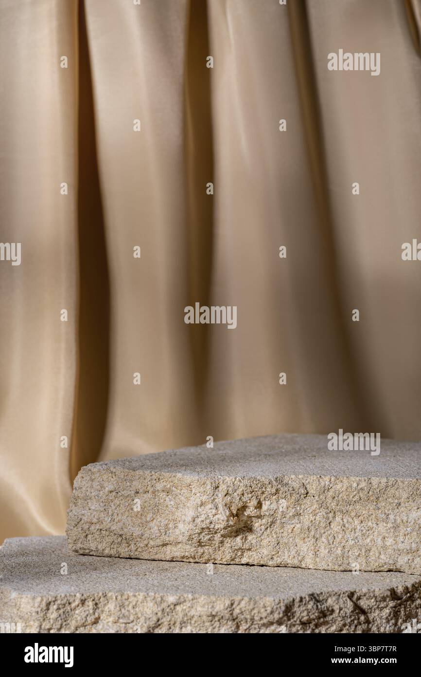 Beige Natursteine Podium auf beigem textilen Vorhang Hintergrund, Plattform für Produktpräsentation. Leer für Modelldesign. Vorderansicht. Kopierbereich Stockfoto