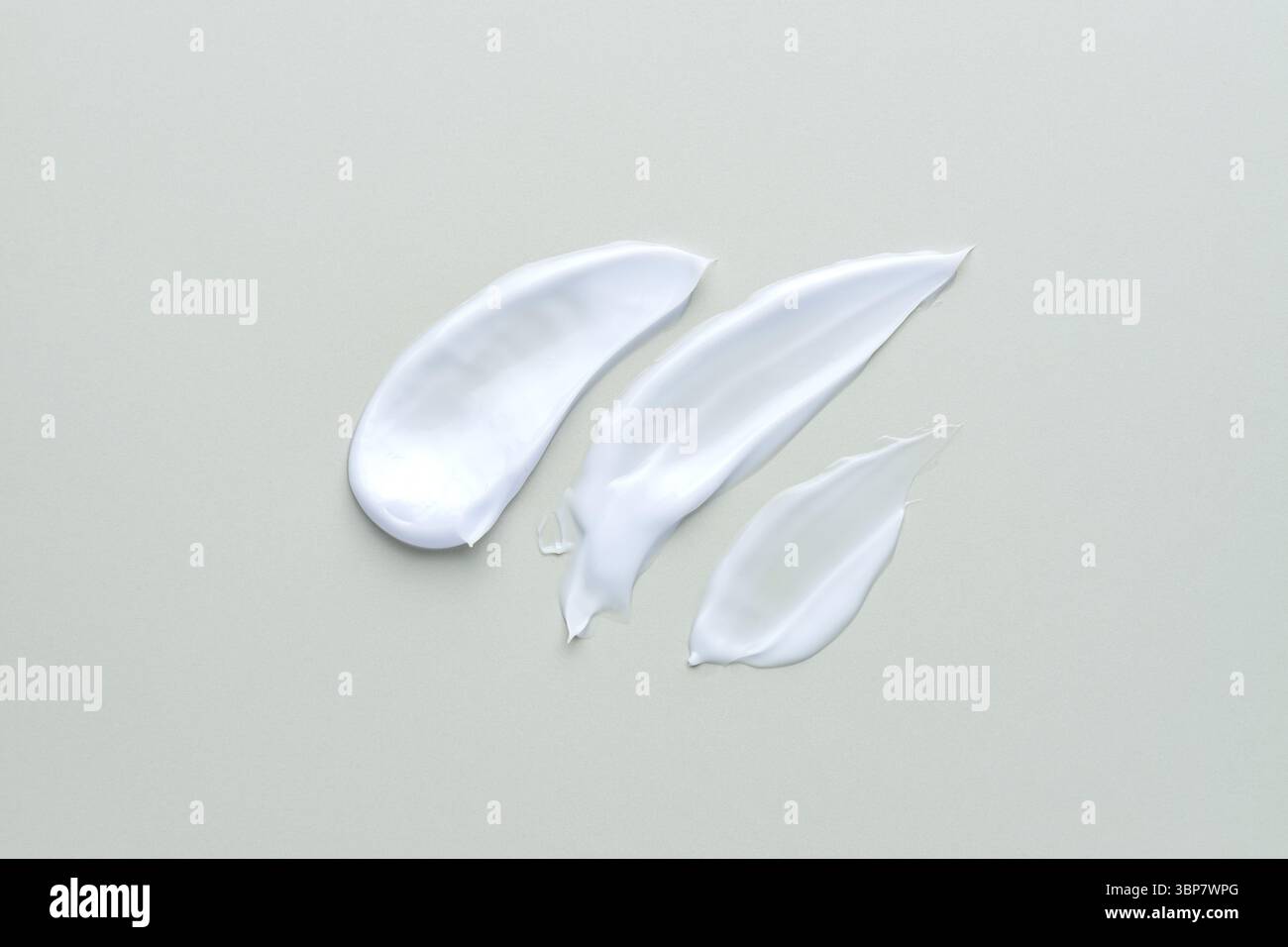 Weiße kosmetische Creme-Lotion mit Feuchtigkeitsspendern auf grauem Hintergrund. Hygiene, Hautpflegeprodukt cremige Textur. Beauty Face Creme Swidge Swatch on Stockfoto