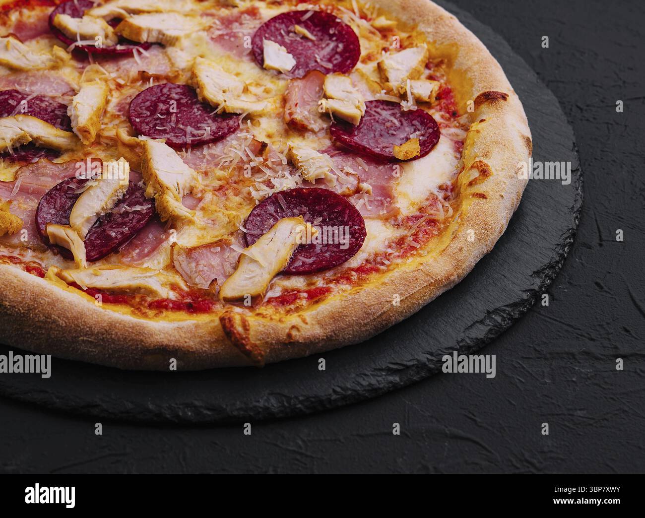 Essen, Peperoni Pizza mit Basilikum und Parmesan Käse auf schwarzem Steinteller Stockfoto