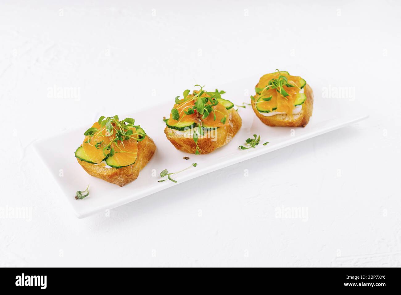 Essen, elegante Lachskanapes mit Mikrogrün auf einem weißen Teller Stockfoto