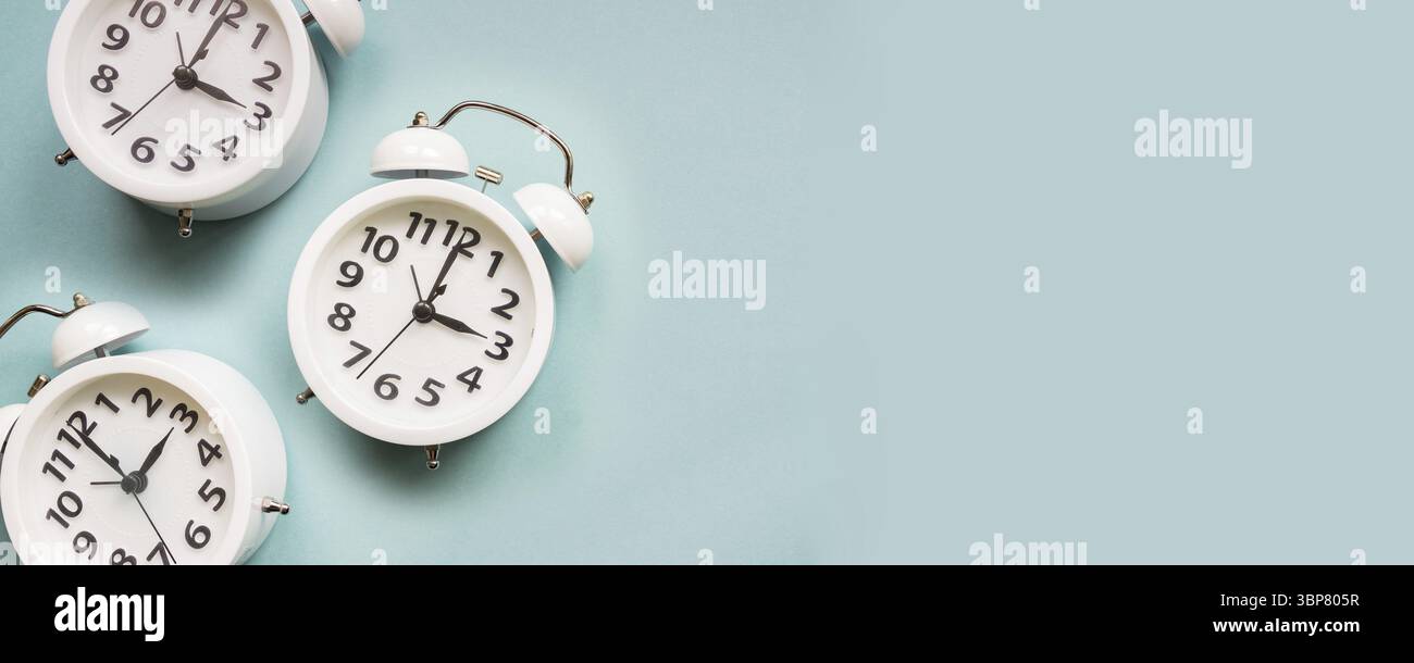 Flacher weißer, schöner neuer Wecker auf blauem Hintergrund. Muster. Kopierbereich Stockfoto