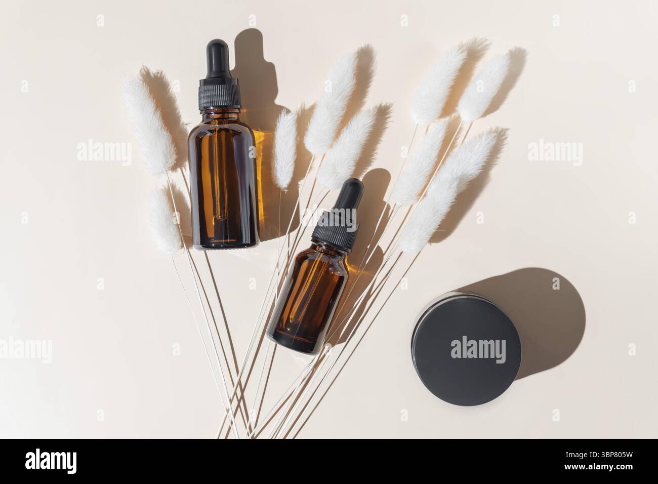Set von Braunglas Kosmetikflaschen auf beigem Hintergrund. Tropfflasche und Creme Tiegel Paket. Hautpflege Schöneitsprodukte Verpackungsdesign für die Stockfoto