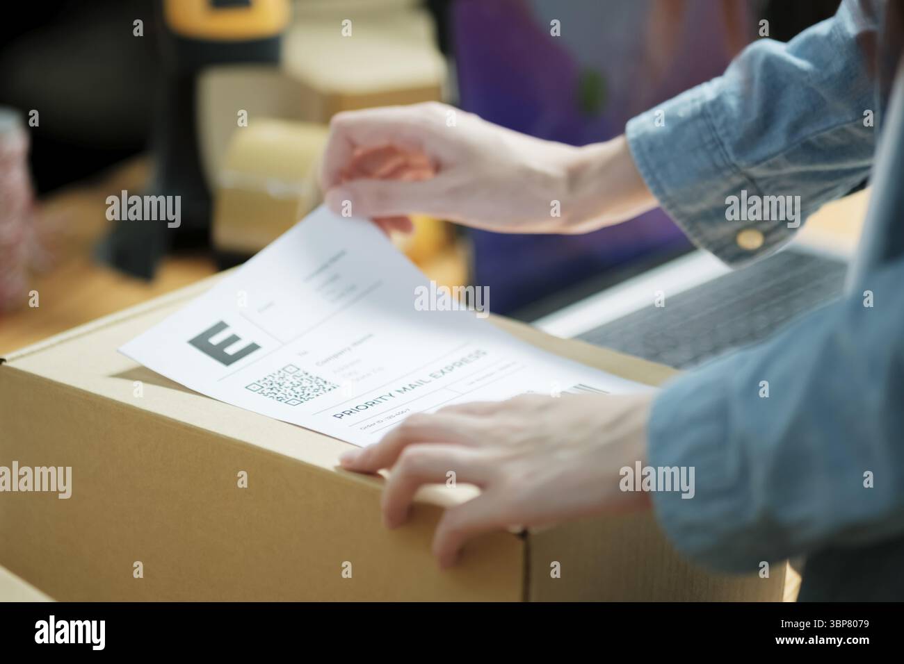 Versandetikett an einem Paket anbringen. Versandvorbereitung für E-Commerce-Unternehmen. Nahaufnahme der Etikettierung von Verpackungen Stockfoto