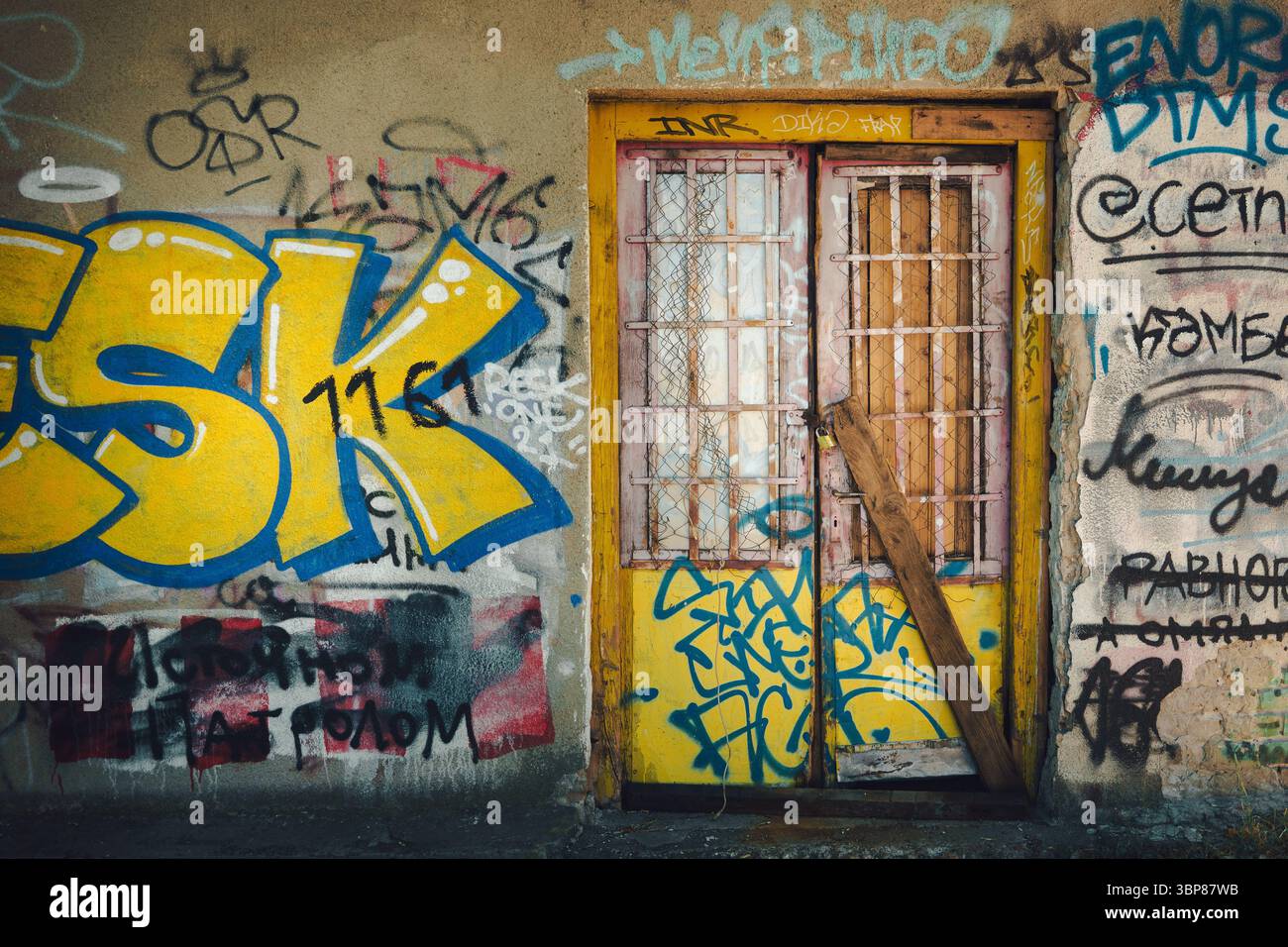Belgrad, Serbien - 04. Juli 2025: Alte gelbe verschlossene Tür in der Mauer mit Graffitis, die Umgebung des Flusses Save am Eingang der Stadt. Stockfoto