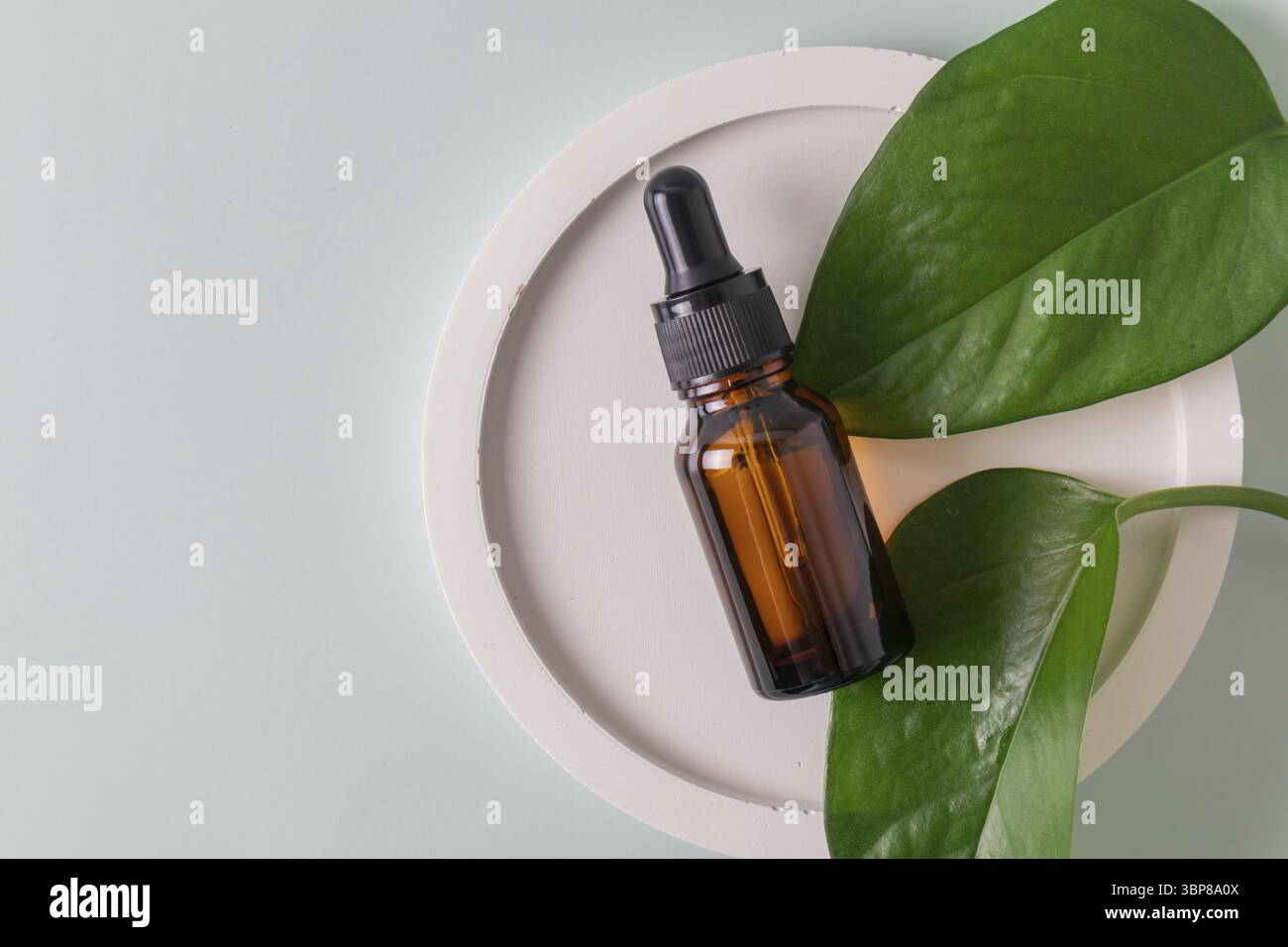 Braunglasflasche mit Pipette mit Serum oder ätherischem Öl auf Betonschale. Hautpflegeprodukte, Naturkosmetik. Schönheitskonzept für Gesicht und Stockfoto