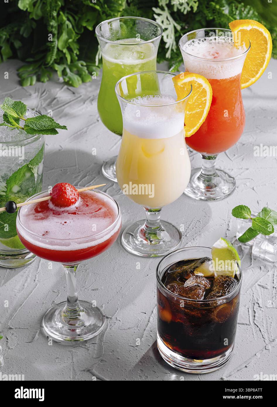 Essen, Auswahl an bunten Cocktails garniert mit Früchten auf einem strukturierten weißen Tisch Stockfoto