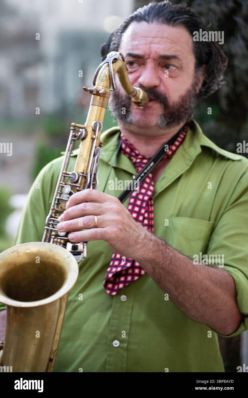Ein leidenschaftlicher Musiker mit Bart und grünem Hemd spielt während einer Live-Aufführung ein goldenes Saxophon. Stockfoto