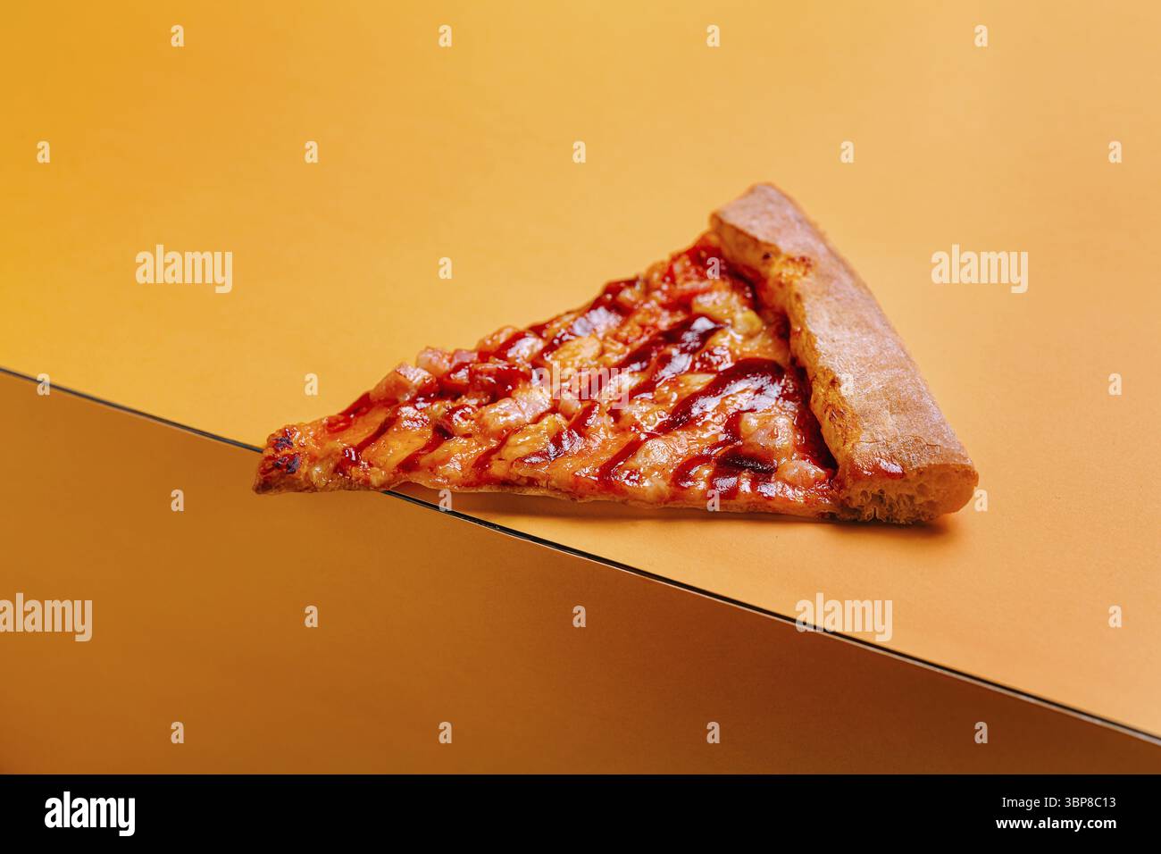 Food, Ein dreieckiges Stück Pizza auf einem leuchtend orangen Hintergrund mit Käse und Belägen. Die Kruste ist goldbraun, perfekt für shari Stockfoto