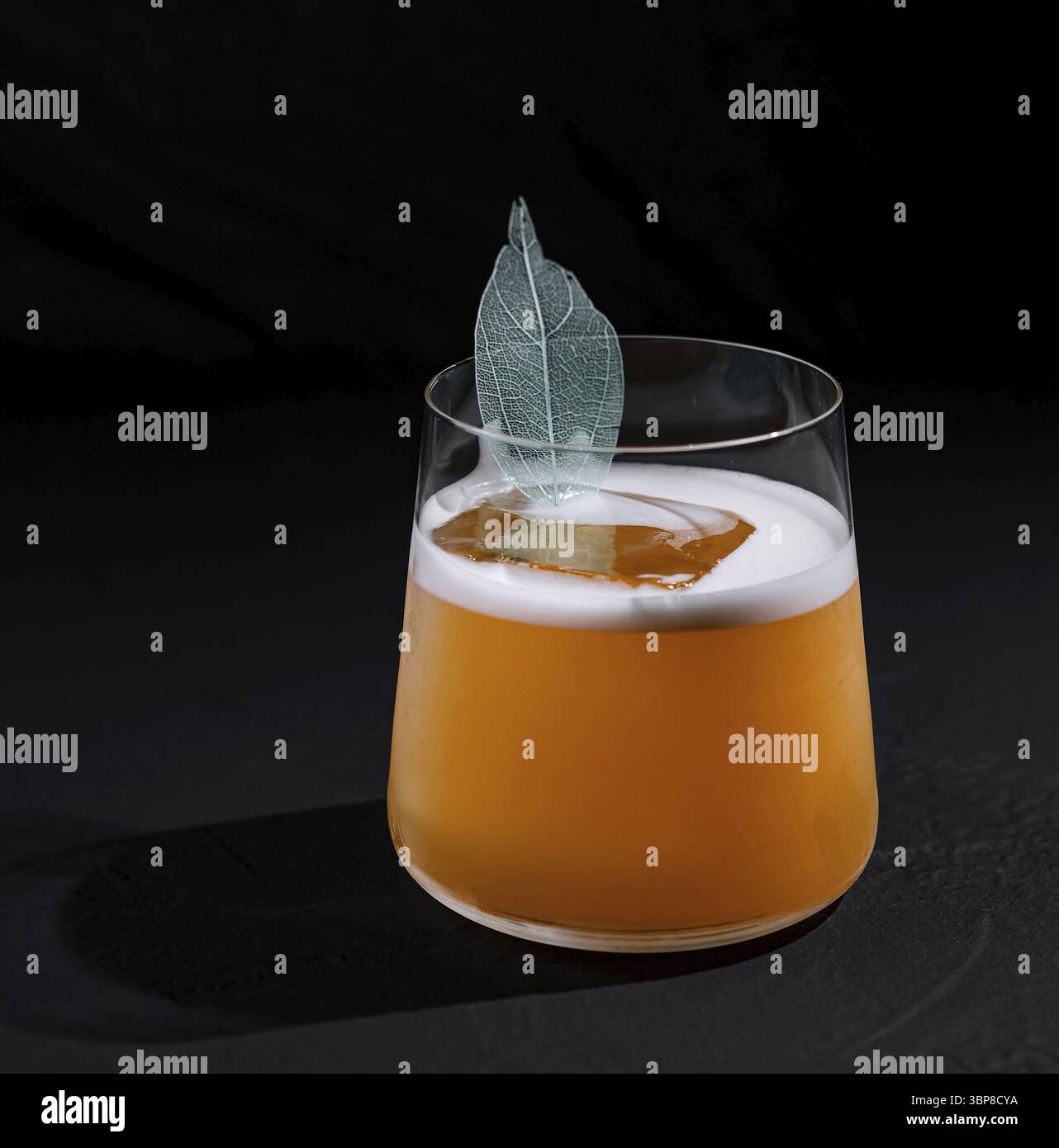 Essen, moderner Cocktail mit einer schaumigen Decke und einer zarten Blattgarnitur, präsentiert vor dunklem Hintergrund Stockfoto