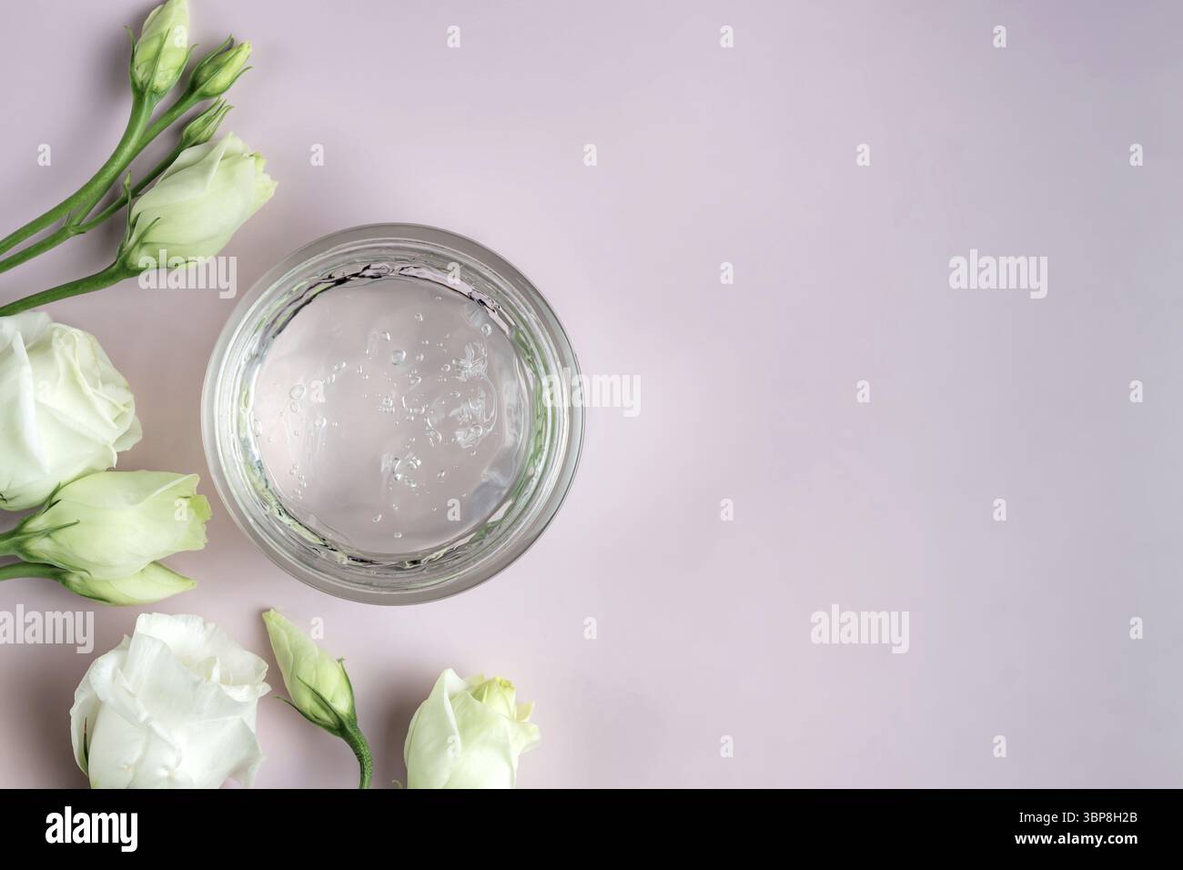 Glas mit transparentem Kosmetikprodukt, Gel oder Creme auf rosafarbenem Hintergrund mit Blumen. Unbranded Paket mit antioxidativer Creme für die Selbstpflege. V Stockfoto