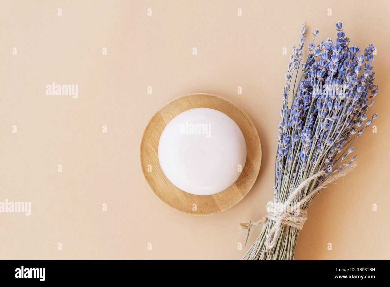 Handgemachte Lavendelseife. Ein Stück Naturseife in Kugelform mit getrockneten Lavendelblüten auf einem Holzteller. Bio-Kosmetik für Hautpflege und Spa Stockfoto