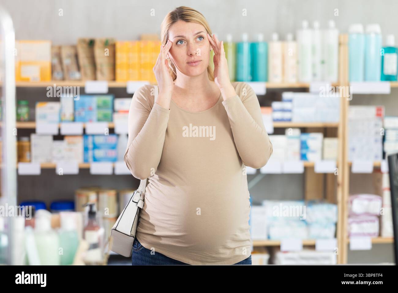 Schwangere Frau besucht Apotheke und leidet an Kopfschmerzen Stockfoto