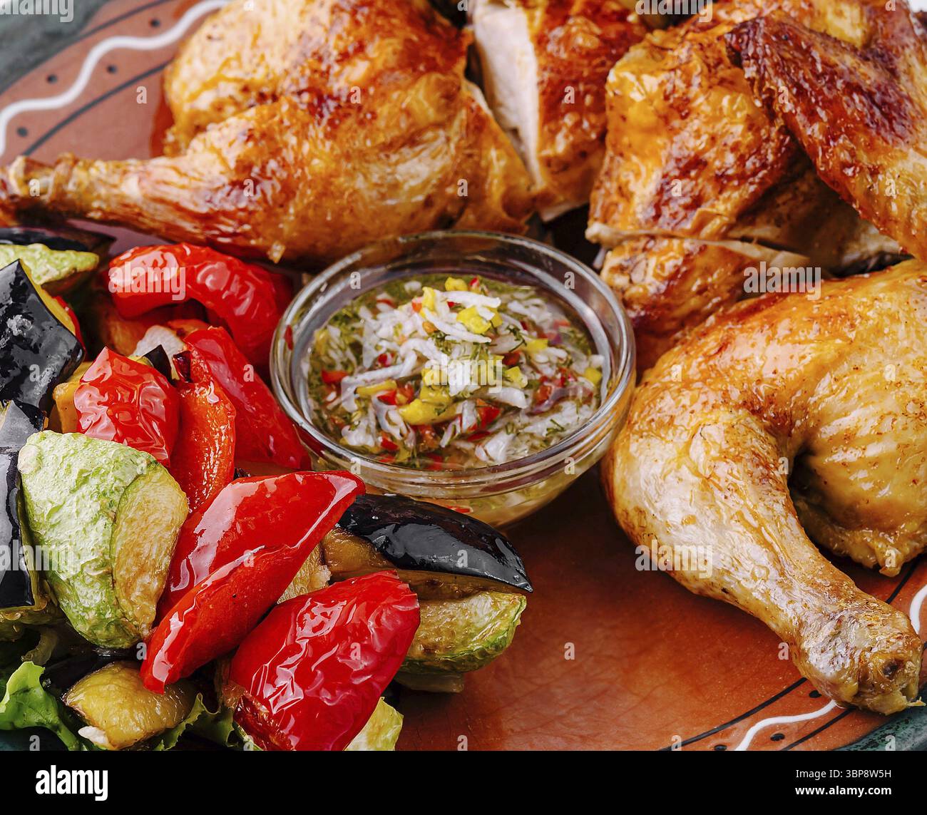Essen, köstliches gebratenes Huhn serviert mit gegrilltem Gemüse und Sauce auf einem rustikalen Teller Stockfoto