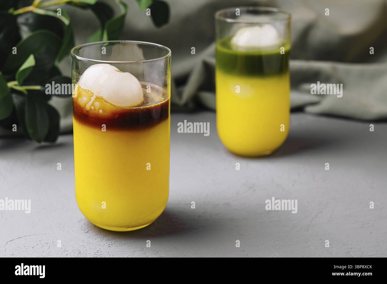 Essen, elegante Gläser mit mehrschichtigen tropischen Cocktails und Eiskugel Stockfoto