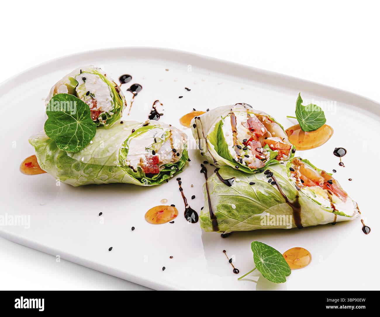 Essen, köstliche Frühlingsbrötchen mit frischem Gemüse, präsentiert auf einem weißen Teller. Garniert mit einem Hauch Soße und Kräutern, perfekt für Stockfoto