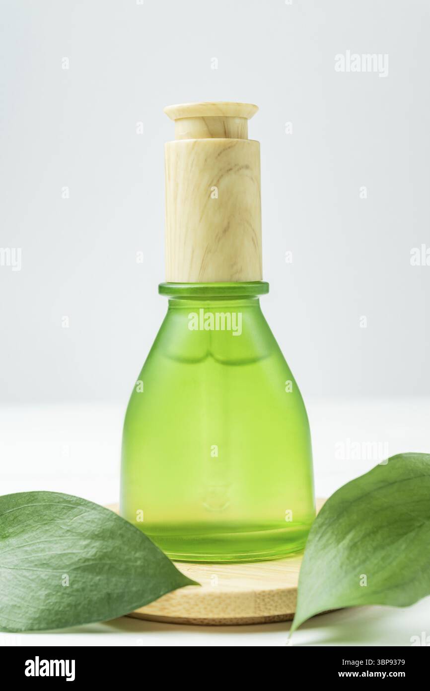 Hyaluronsäure-Öl-Mockup mit Kollagen und Peptiden in grüner Flasche auf Holzspiel mit grünen Blättern. Hautpflege Beauty-Produkt flüssige kosmetische Serum Stockfoto