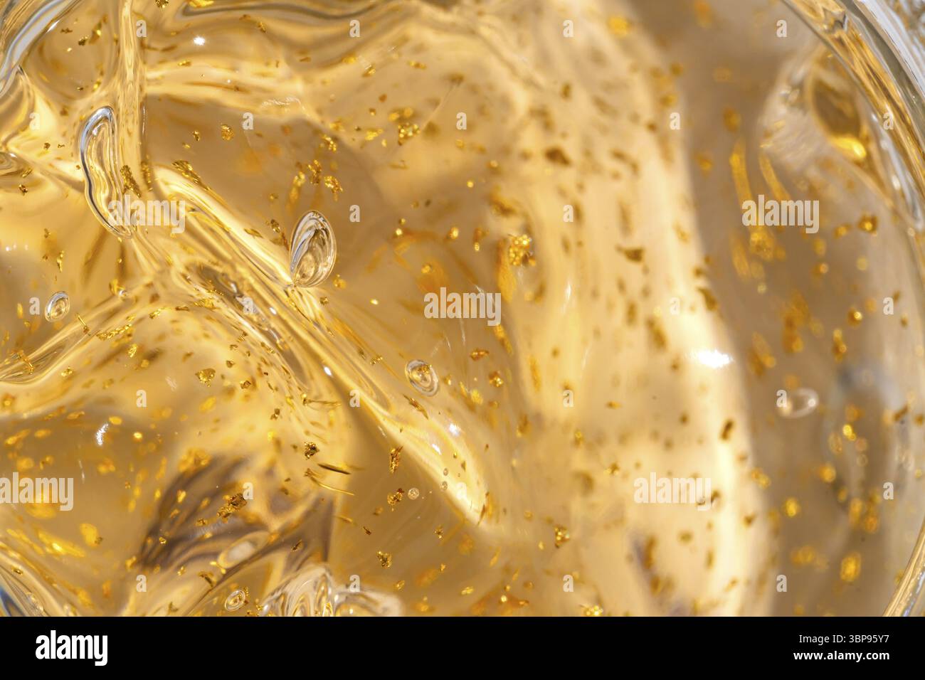 Texturhintergrund des 24k Gold Hautpflegegels mit goldenen Partikeln für ältere Haut. Makro zur Darstellung der Textur von Schönheitsprodukten Stockfoto