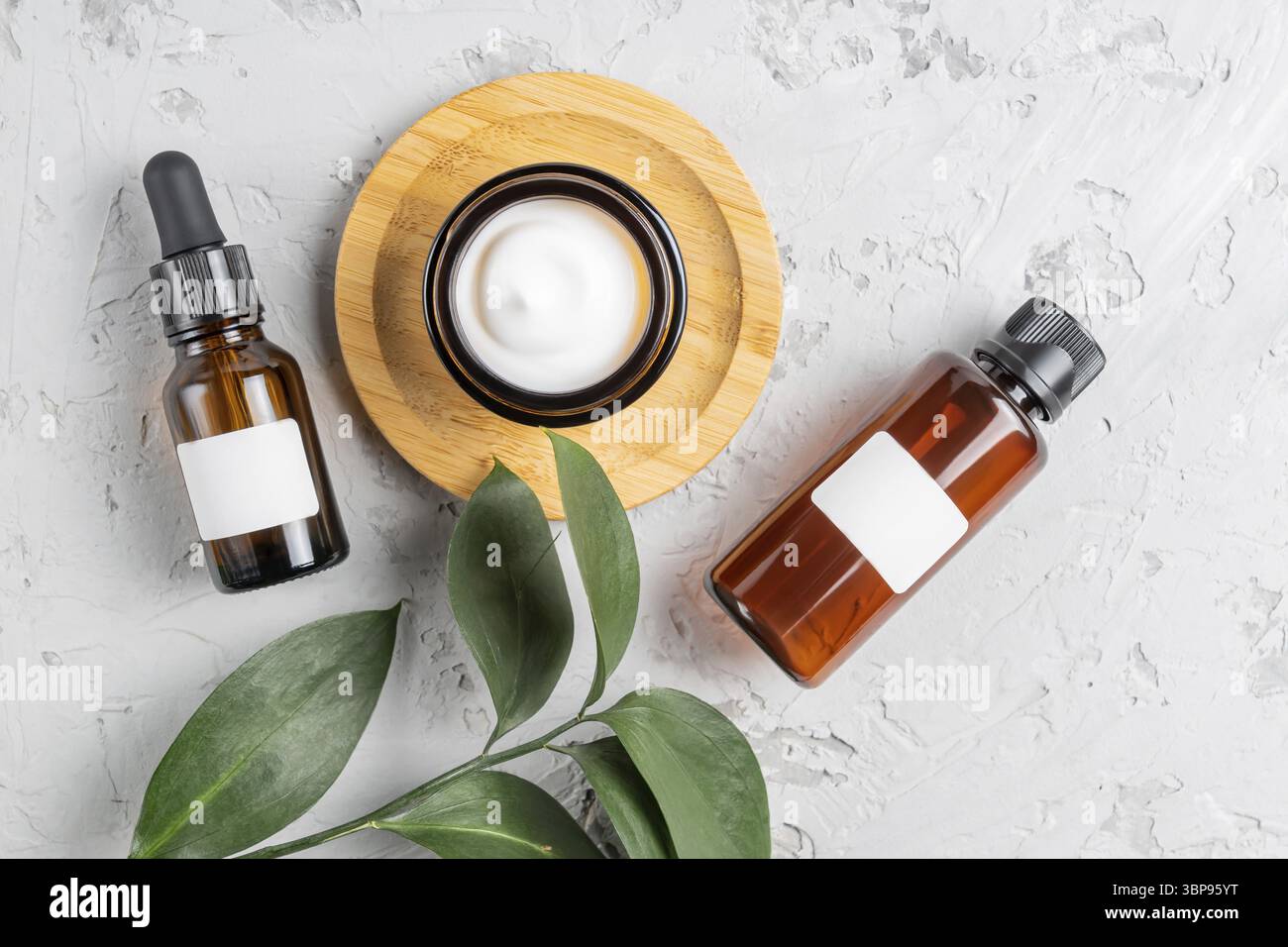 Feuchtigkeitscreme-Glas, Serum in Glasflasche und Toner mit grünen Blättern auf Beton Hintergrund. Flach liegend, Draufsicht. Set für Haut- und Körperpflege-Schönheit Stockfoto