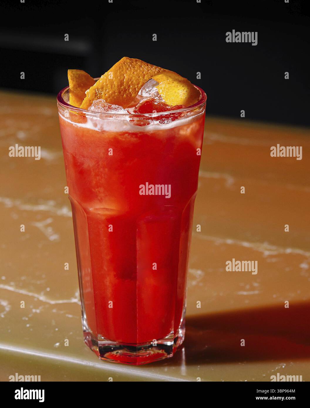 Das Essen, ein vibrierender roter Cocktail mit Zitrusgarnitur, serviert auf einer Hochglanzbar Stockfoto