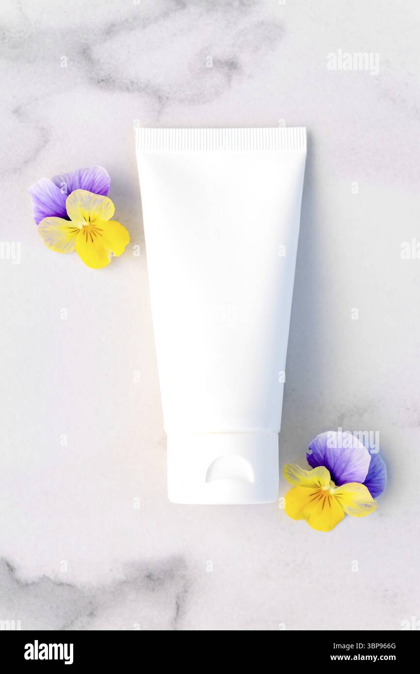 Mockup von weißen Squeeze-Flasche kosmetische Creme Tube für Branding von Medizin oder Kosmetik - Shampoo, Gel, Hautpflege. Feuchtigkeitscreme leere Flasche und Stiefmütterchen Stockfoto