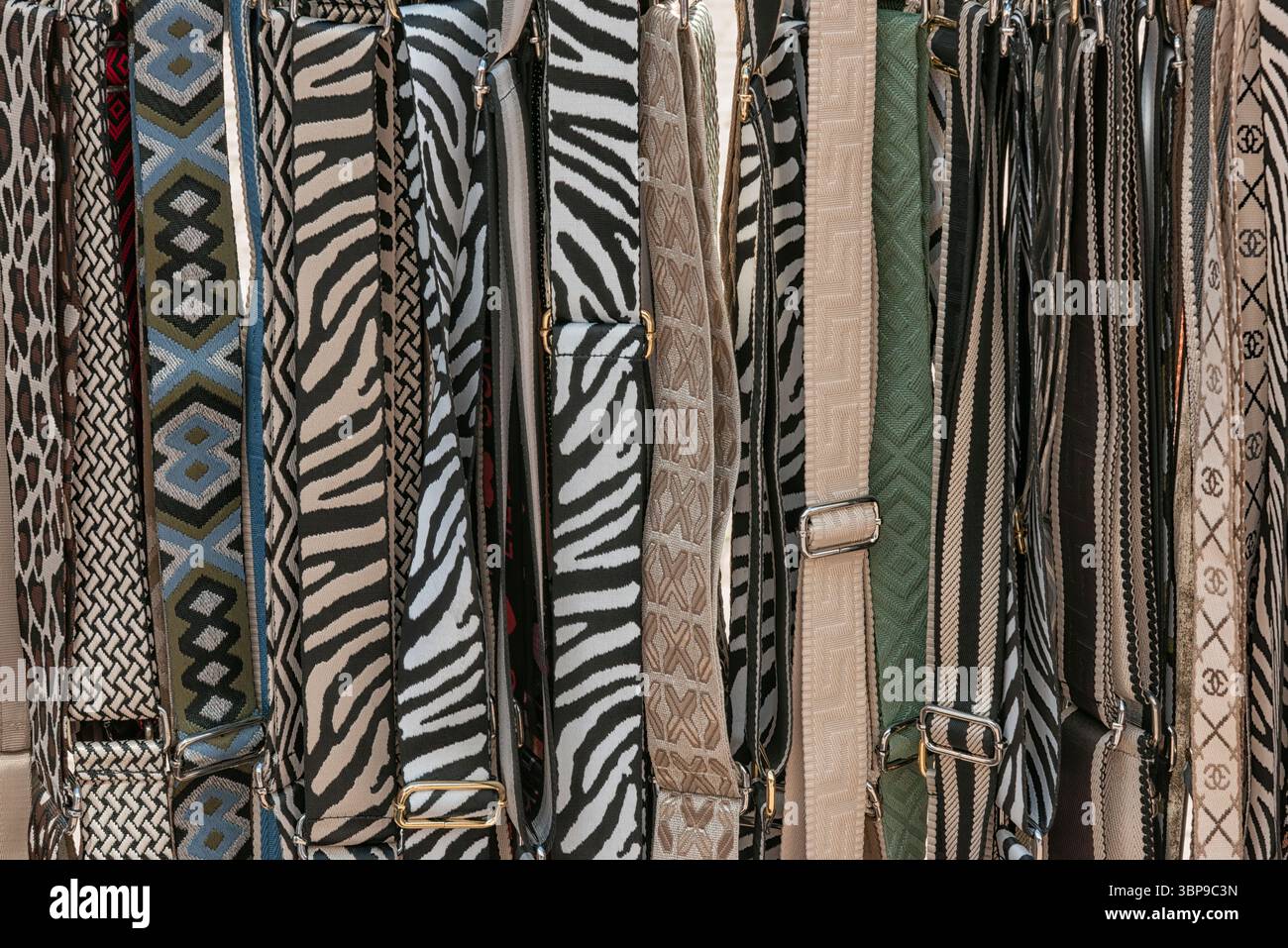 Stylische Taschen mit verschiedenen Mustern hängen in einem Geschäft und präsentieren modische Accessoires. Stockfoto