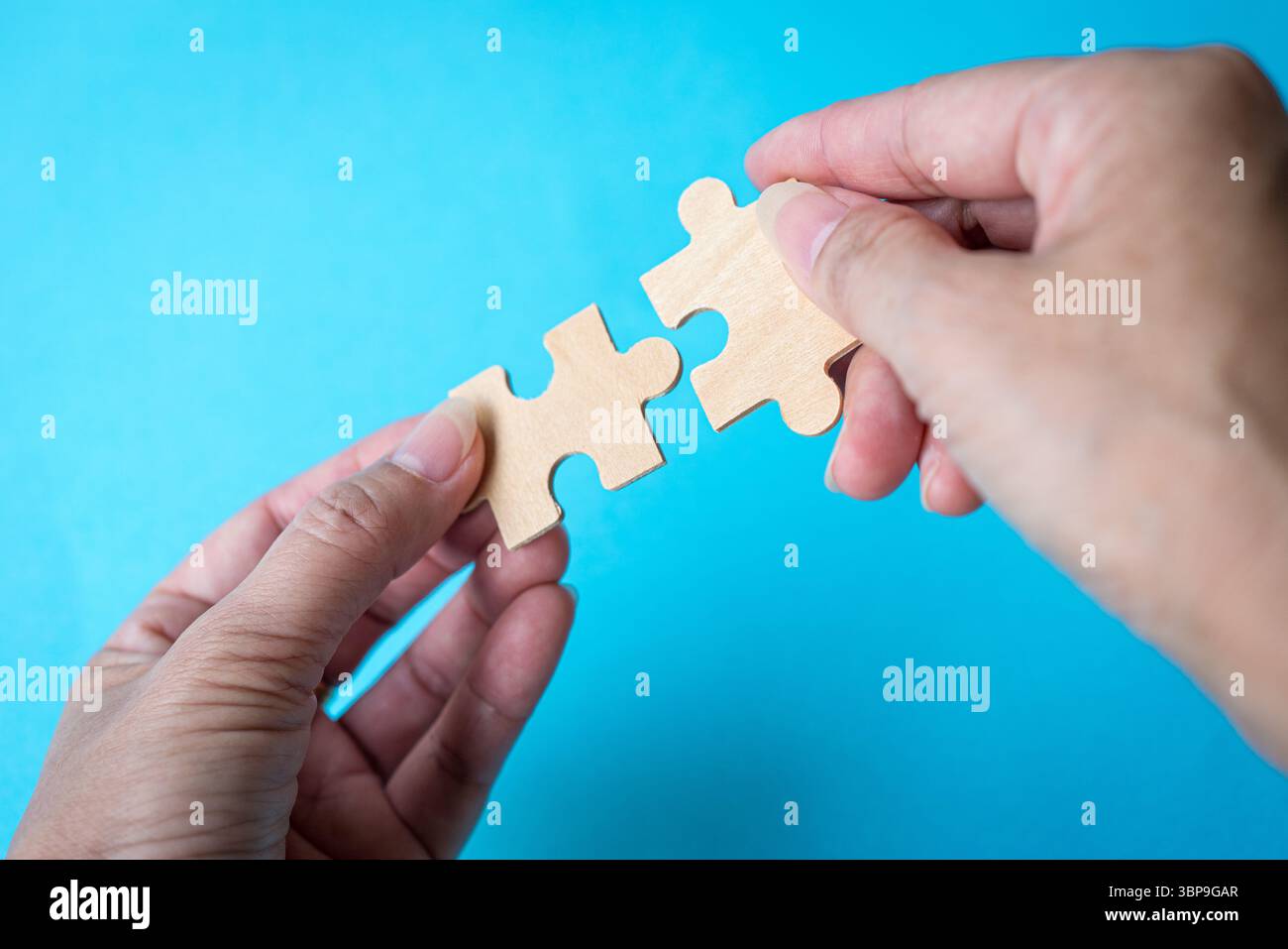 Puzzleteile halten. Vor blauem Hintergrund. Abgleich- oder Kooperationskonzept. Stockfoto