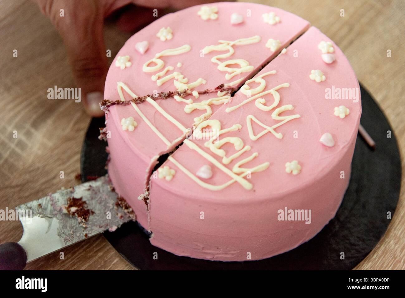 Pinkfarbene Haustorte mit einer Inschrift zum Geburtstag eines Mädchens, drei Jahre alt Stockfoto