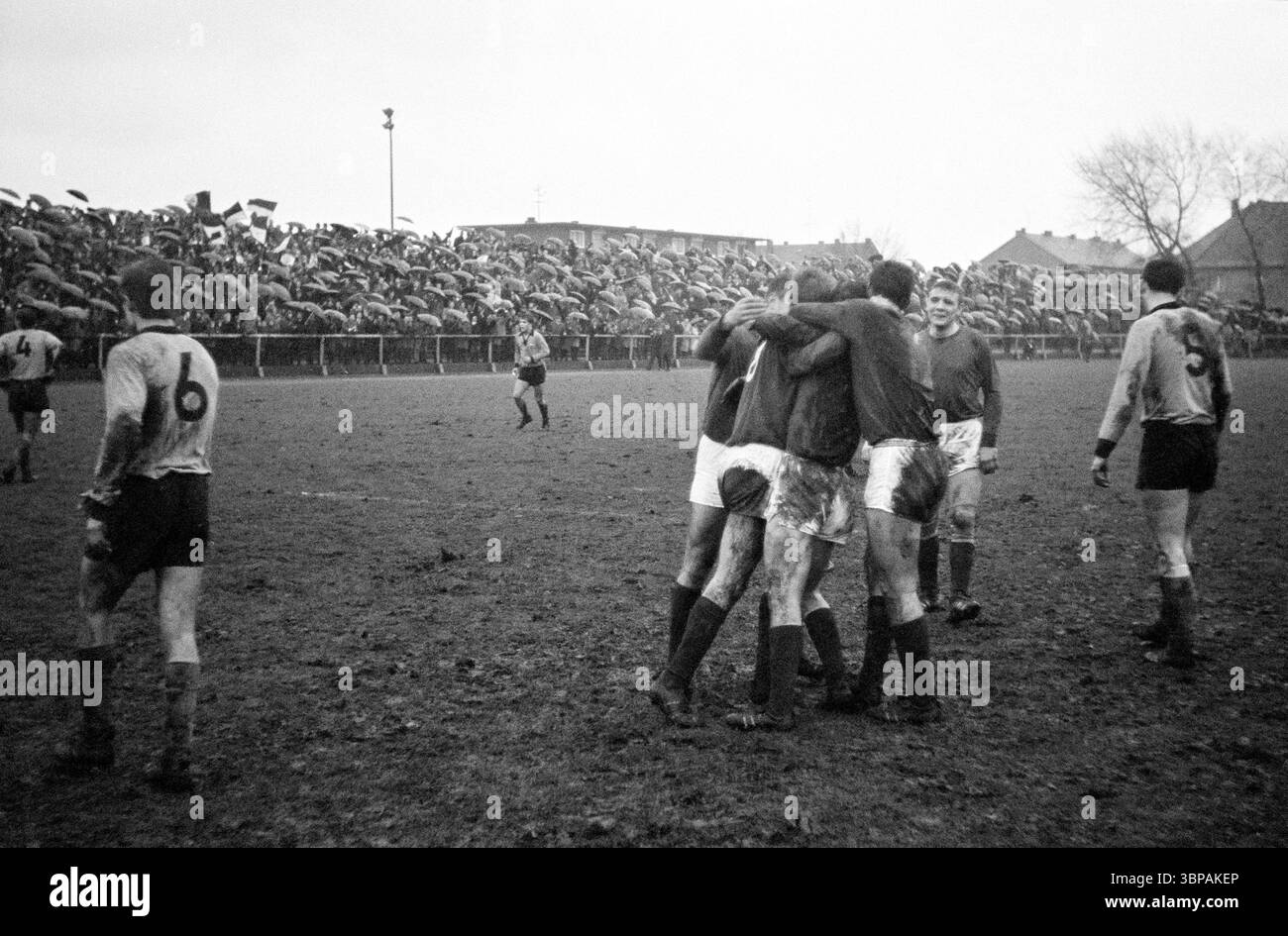 60er Jahre, Sport, Fußball, Regionalliga West, 1965/1966, STV Horst-Emscher vs. Rot-Weiss Essen 1-2, 02.01.1966, Fürstenberg-Stadion in Gelsenkirchen-Horst, freut sich über das Tor 1-2 von Willi Ente Lippens (RWE), 2.f.r Manfred Frankowski (RWE), ungedecktes Stadion, Besucher mit Schirmen Stockfoto