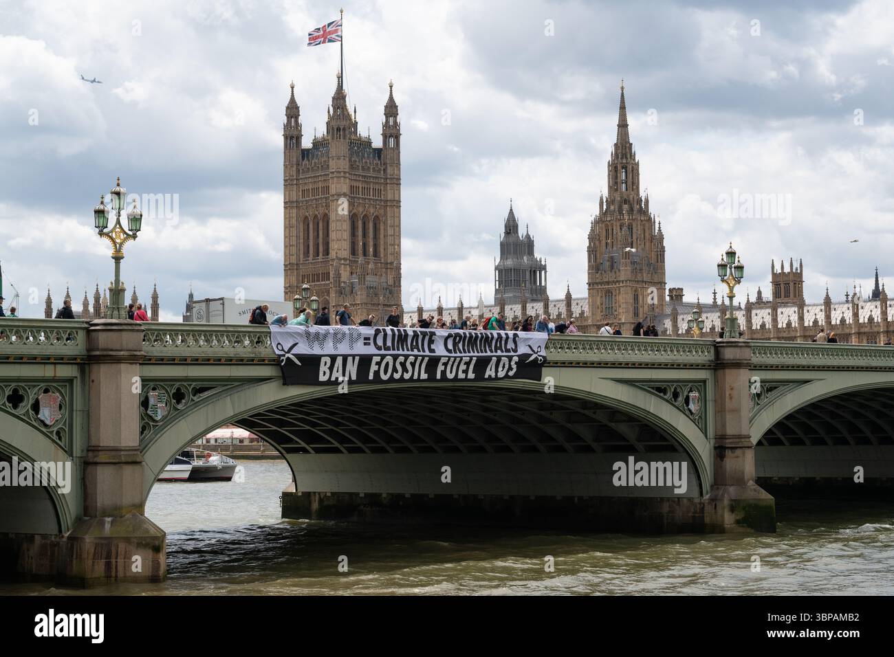 London, Großbritannien. 7. Juli 2025. Klimaaktivisten lassen ein Banner von der Westminster Bridge fallen, mit den Houses of Parliament im Hintergrund, vor einer Debatte der Abgeordneten über eine Petition zum Verbot von Werbung und Sponsoring für fossile Brennstoffe. Die Petition, die vom Naturforscher, Fernsehmoderator und Autor Chris Packham aufgeworfen wurde, erhielt über 100.000 Unterschriften und sagt, dass der fortgesetzte Verbrauch fossiler Brennstoffe mehr Menschen töten wird als das Rauchen, für das 2002 Werbung verboten wurde. Quelle: Ron Fassbender/Alamy Live News Stockfoto