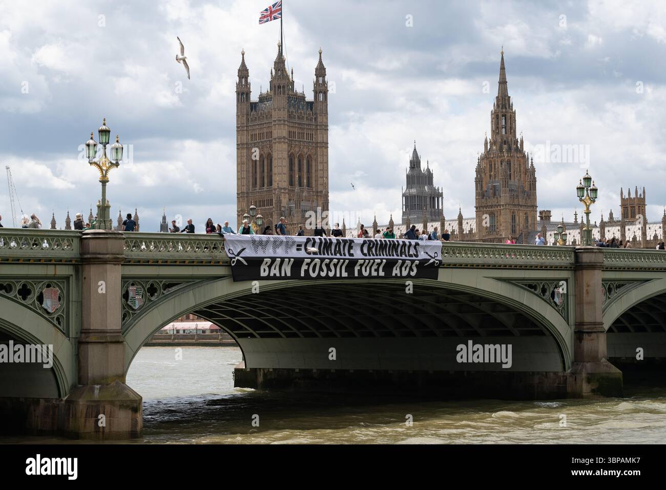 London, Großbritannien. 7. Juli 2025. Klimaaktivisten lassen ein Banner von der Westminster Bridge fallen, mit den Houses of Parliament im Hintergrund, vor einer Debatte der Abgeordneten über eine Petition zum Verbot von Werbung und Sponsoring für fossile Brennstoffe. Die Petition, die vom Naturforscher, Fernsehmoderator und Autor Chris Packham aufgeworfen wurde, erhielt über 100.000 Unterschriften und sagt, dass der fortgesetzte Verbrauch fossiler Brennstoffe mehr Menschen töten wird als das Rauchen, für das 2002 Werbung verboten wurde. Quelle: Ron Fassbender/Alamy Live News Stockfoto