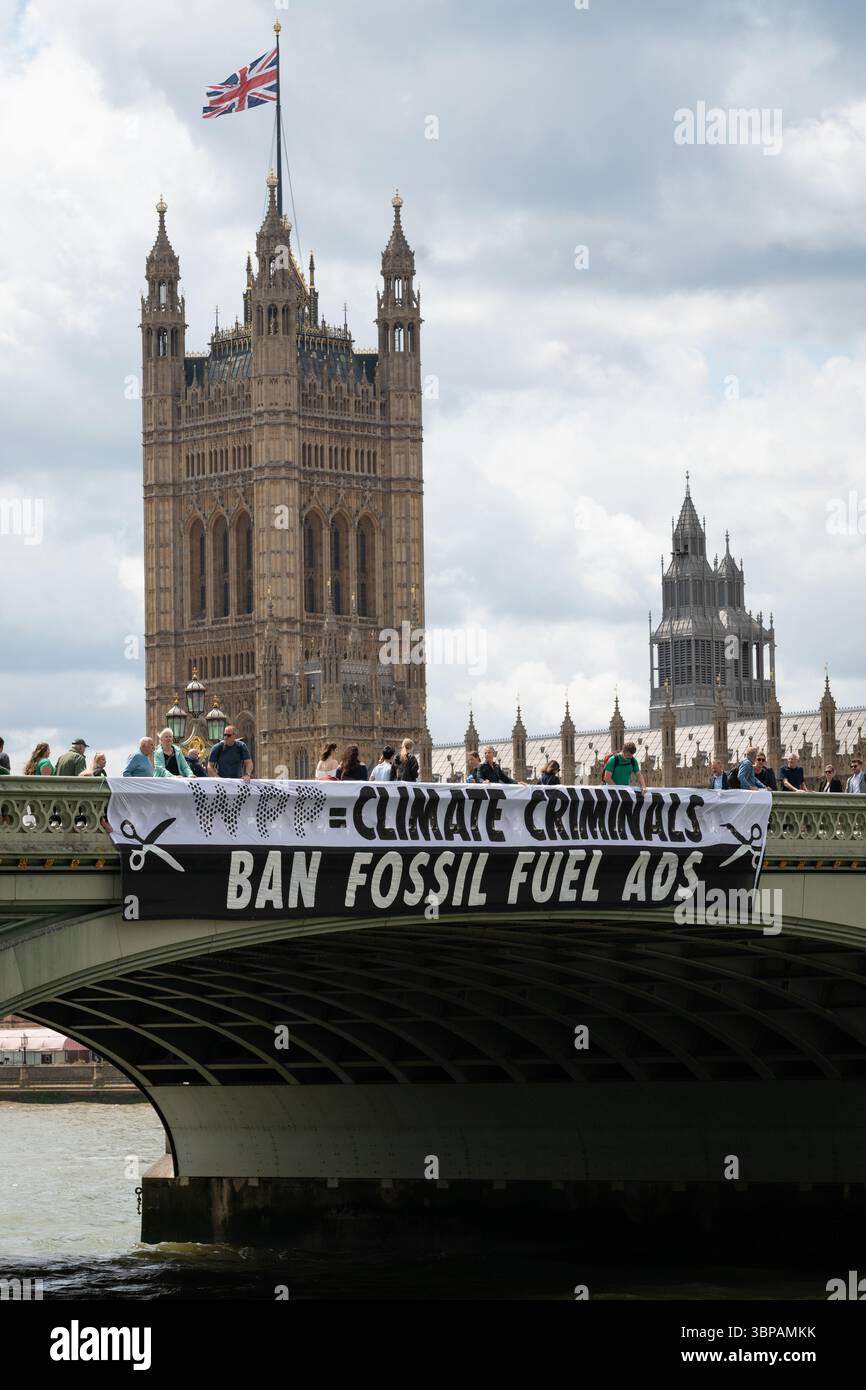 London, Großbritannien. 7. Juli 2025. Klimaaktivisten lassen ein Banner von der Westminster Bridge fallen, mit den Houses of Parliament im Hintergrund, vor einer Debatte der Abgeordneten über eine Petition zum Verbot von Werbung und Sponsoring für fossile Brennstoffe. Die Petition, die vom Naturforscher, Fernsehmoderator und Autor Chris Packham aufgeworfen wurde, erhielt über 100.000 Unterschriften und sagt, dass der fortgesetzte Verbrauch fossiler Brennstoffe mehr Menschen töten wird als das Rauchen, für das 2002 Werbung verboten wurde. Quelle: Ron Fassbender/Alamy Live News Stockfoto