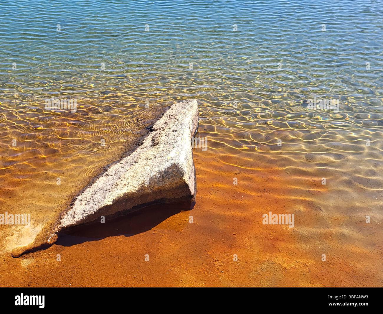 Bergsee mit sichtbarem Stein und rotem Wasser, verfärbt durch Eisengehalt in den Schweizer Alpen Stockfoto
