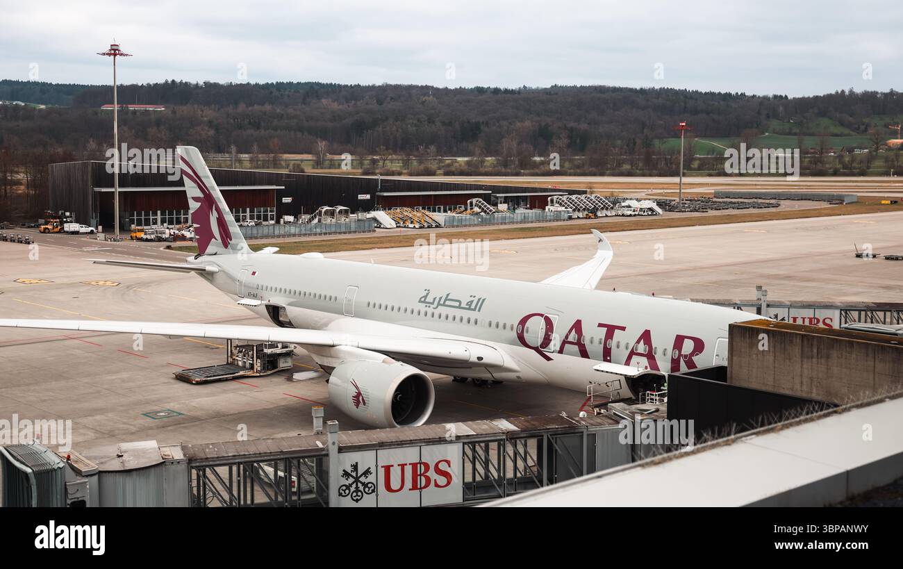 Ein Flugzeug aus Katar parkt am Flughafen Zürich unter grauem Himmel und bietet eine ruhige Umgebung am geschäftigen Reisetoto. Stockfoto